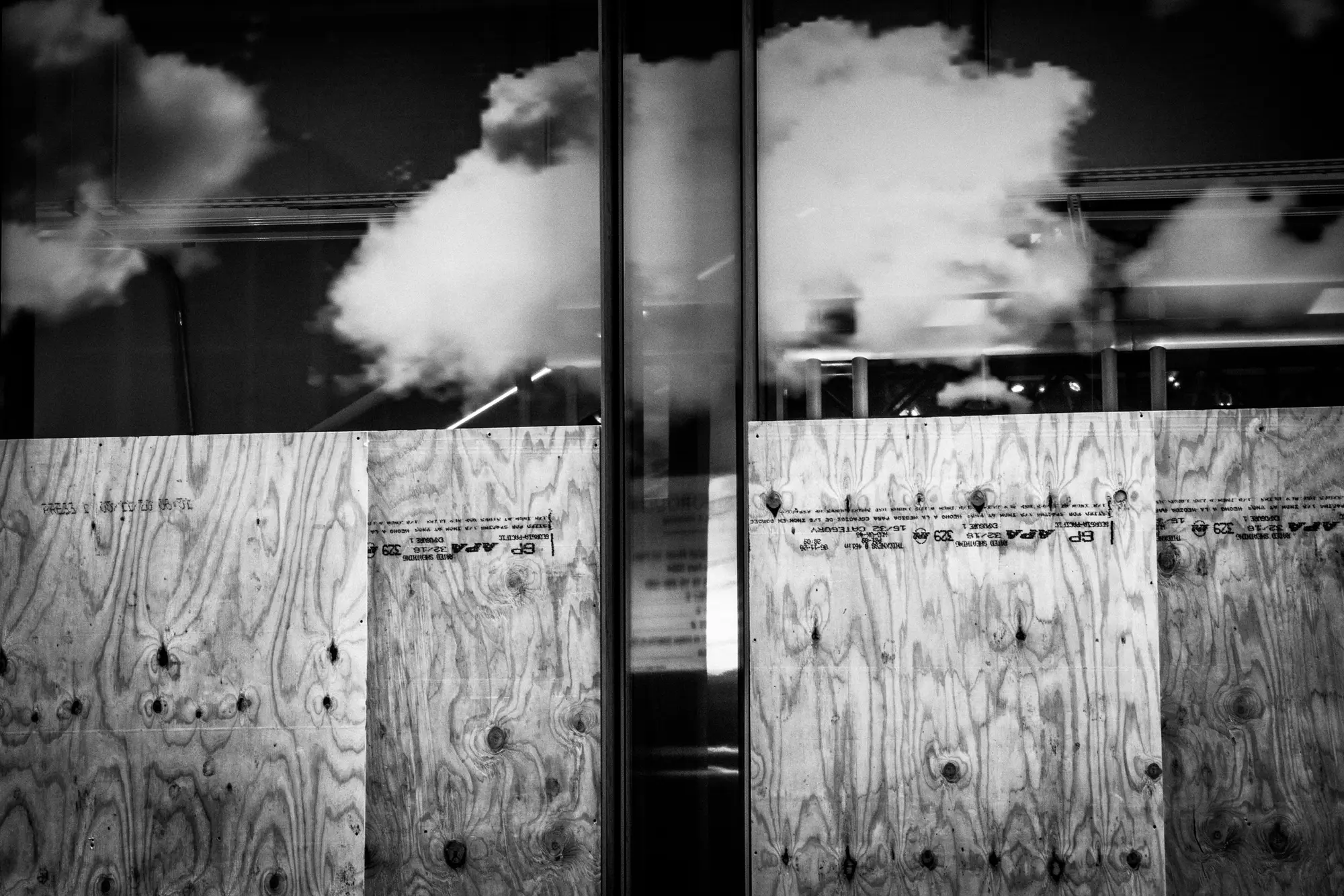 Clouds reflected above a boarded facade