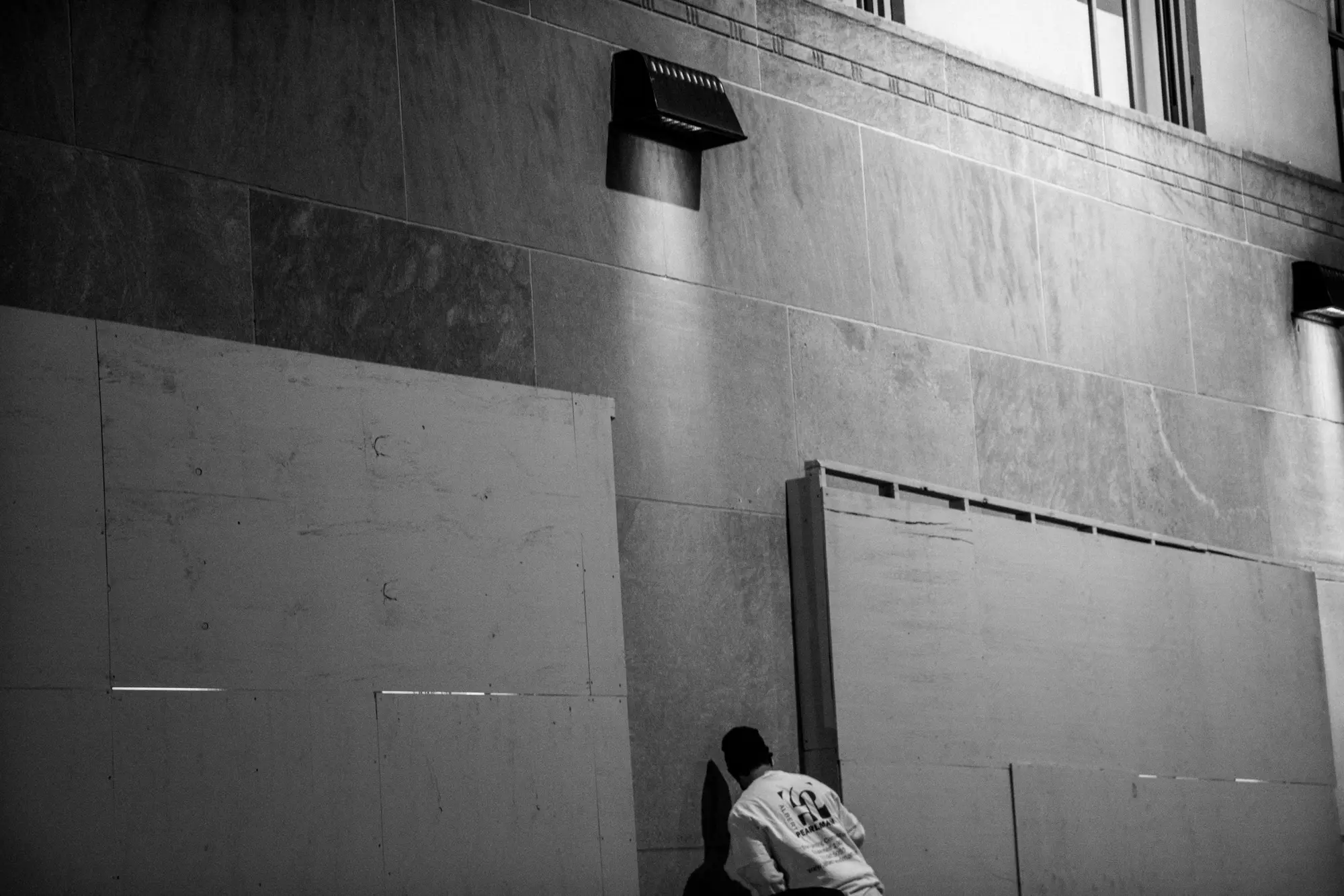 A seated figure beside a blank wall